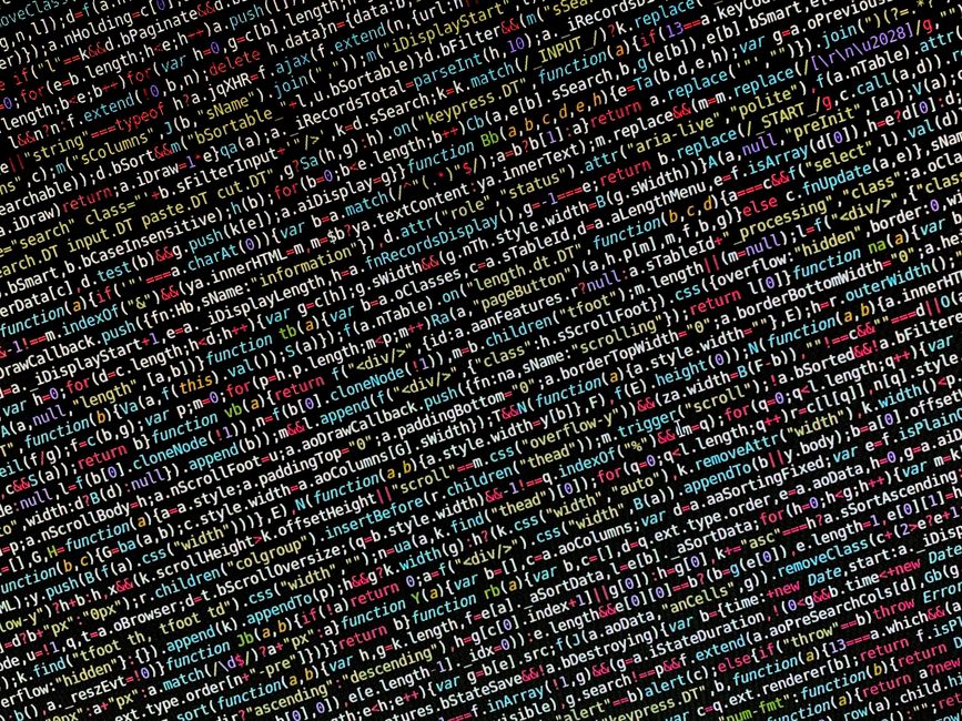 A close-up view of a laptop placed on a desk displaying a coding interface with colorful syntax highlighting on the left side and a large orange calculator application on the right side of the screen.